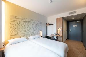 维里埃特B&B HOTELS Bourg-en-Bresse Viriat的卧室配有一张白色大床和木墙