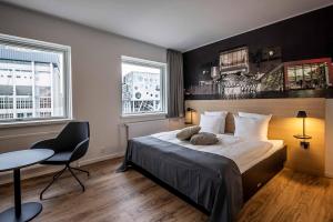 奥尔堡KOMPAS Hotel Aalborg的一间卧室配有一张床、一张桌子和两个窗户