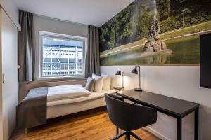 奥尔堡KOMPAS Hotel Aalborg的一间卧室配有一张床、一张书桌和一个窗户。