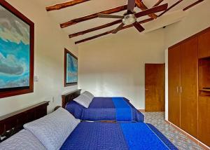 圣罗莎德卡瓦尔Hotel Finca Del Café的一间卧室配有蓝色的床和吊扇