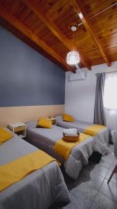 门多萨Hotel Alta Mendoza的客房设有4张带黄床单和木制天花板的床。