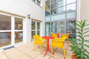 维勒班Appart'City Classic Lyon Villeurbanne的庭院设有黄色椅子和红色桌子