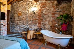 卢卡Luxury Corte Di Re Artù的一间砖墙内带浴缸的浴室的卧室