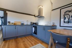 考文垂Coventry Historic Houses的厨房配有蓝色橱柜和木桌