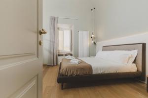 拉奎拉Casa Horti Suites的一间卧室配有一张带白色床单和镜子的床