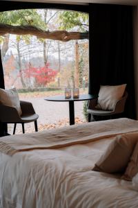 亨法尔Chambres d'hôtes Eucalyptus et Glycine的一间卧室配有一张床、一张桌子和一个窗户。