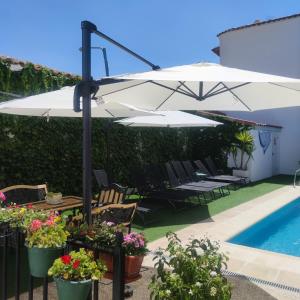 Casa Capricho del Destino的游泳池旁带桌子和遮阳伞的天井