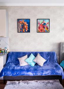 阿拉木图Апартаменты с этническими мотивами с видом на горы的客厅里一张蓝色的沙发,墙上有三幅画