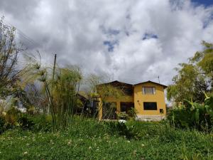 拉卡莱拉Iwoka Ecoturismo的坐落在郁郁葱葱的绿色田野顶部的黄色房子