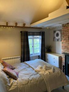 普尔伯勒Pieman's Cottage - Pulborough, West Sussex Cottage - sunny courtyard的一间卧室配有带毛巾的床