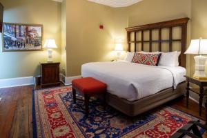 萨凡纳The Marshall House, Historic Inns of Savannah Collection的一间卧室配有一张带红色凳子和两盏灯的床。