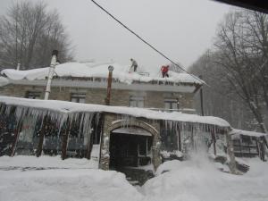 哈尼亚To Hani Tou Kokkini, Pelion的两人在雪覆盖的房子屋顶上