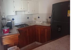 Puerto ViejoCondominio Victoria Real - Apartamento 202的厨房配有木制橱柜和黑色冰箱。