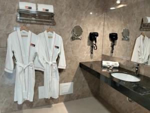 利马SM HOTEL Plus的浴室设有白色浴袍、一个柜台和水槽