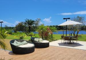 瓜拉久巴Lindo flat, na beira do lago, na melhor praia da Bahia的庭院配有两把椅子、一张桌子和一把遮阳伞