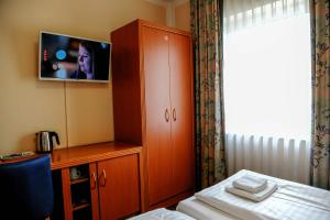汉诺威奥派酒店的一间卧室设有带电视的橱柜