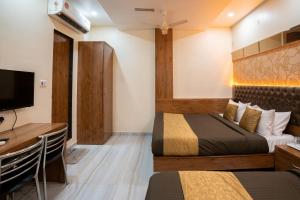 孟买Hotel Royce Executive Near US Consulate, Bandra Kurla Complex的一间卧室配有两张床、一张桌子和一台电视。
