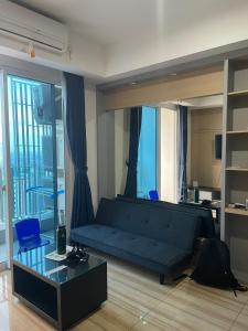 DukuhpakisLuxury Apartemen Grand Lagoon Sungkono Surabaya的客厅配有蓝色的沙发和玻璃桌