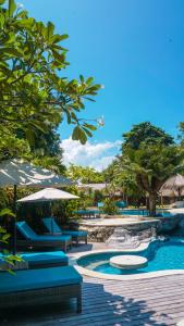 蓝梦岛海潮海滩度假酒店的一个带蓝色椅子和遮阳伞及树木的游泳池