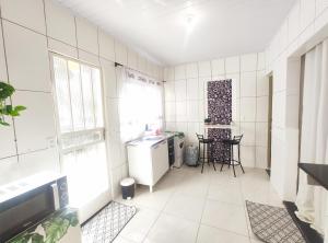 贝洛奥里藏特Kitnet Lua - Mobiliada的厨房设有白色瓷砖墙壁和桌椅