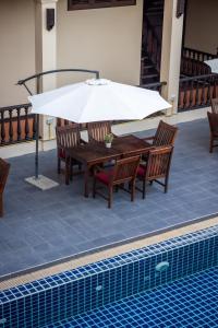 琅勃拉邦沙达酒店的游泳池旁配有遮阳伞的桌椅