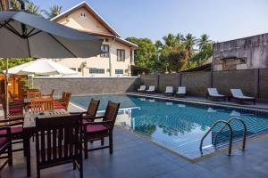 琅勃拉邦沙达酒店的一个带桌椅和遮阳伞的游泳池