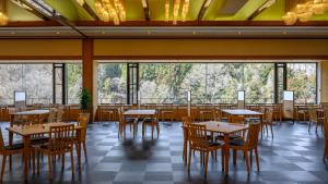 涩川市福一酒店的用餐室配有桌椅和大窗户