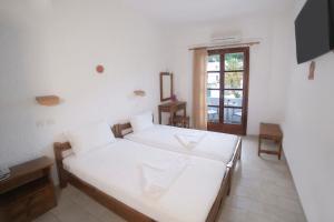 阿基奥斯基利考斯奥伊诺伊旅馆的一间白色卧室,配有两张床和窗户