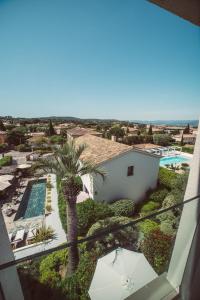 圣特罗佩Hotel le Mandala的阳台享有游泳池和棕榈树美景。