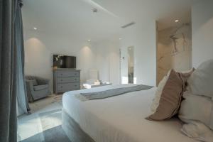 圣特罗佩Hotel le Mandala的卧室配有一张白色大床和一把椅子