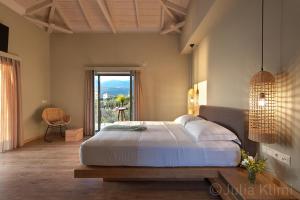 卡德哈米利Diapori Suites Hotel的一间卧室设有一张大床和一个大窗户