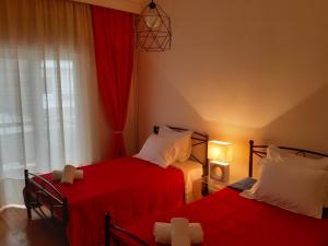 特里卡拉Elegante apartamento centrale的一间卧室设有两张带红色床单的床和窗户。