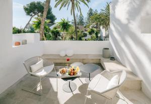 马贝拉Puente Romano Beach Suites - private apartaments的阳台配有桌椅和棕榈树。