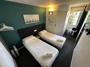 阿莱斯L'Escale d'Alès HOTEL的酒店客房设有两张床和绿色的墙壁。