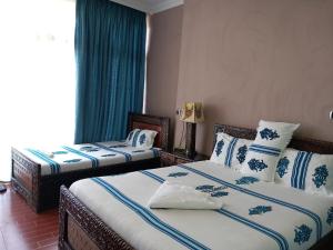 拉利贝拉Blue Nile Guest House的一间卧室配有两张带蓝白色枕头的床