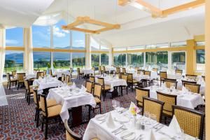 基拉尼Castlerosse Park Resort Holiday Homes的餐厅设有白色的桌椅和窗户。