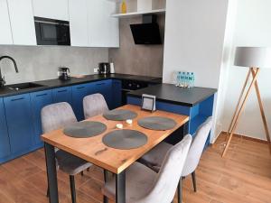 卡托维兹Kima Apartament Bażantów 44的厨房配有木桌和蓝色橱柜。