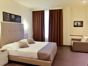 米兰Duomo Hotel & Apartments的酒店客房带一张大床和一把椅子