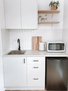 沃纳姆堡The Hideaway - Guest House的白色的厨房配有水槽和微波炉