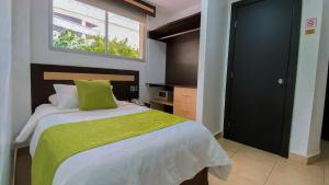 瓜亚基尔MC Suites Boutique的一间卧室配有一张带绿毯的床和窗户。