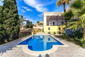 Banyeres del PenedesCatalunya Casas Impressive and Idyllic mansion for up to 40 people!的棕榈树黄色房子前面的游泳池