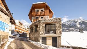 沃雅尼Madame Vacances Hotel Les Cimes的山前雪覆盖道路上的建筑