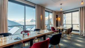 沃雅尼Madame Vacances Hotel Les Cimes的餐厅设有桌椅和大窗户。