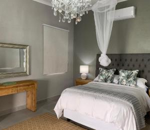 雾观Hazyview Accommodation, Bon Repose Cottages 3&4的一间卧室配有一张床、镜子和吊灯