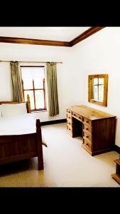 阿马Ridge Wood House的一间卧室配有一张床、一张书桌和一面镜子