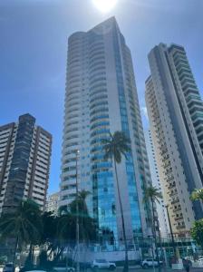 累西腓202 Flat Beira Mar Av Boa Viagem com Cozinha的一座高大的建筑,前面有棕榈树