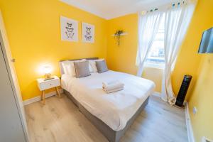 伦敦[COVENT GARDEN] Apartment in Central London的一间卧室设有一张黄色墙壁和窗户的床