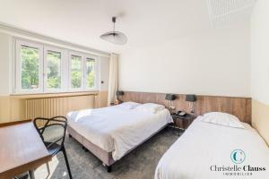坦恩Hotel Restaurant au Floridor的一间卧室设有两张床、一张桌子和窗户。
