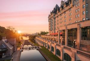 渥太华Fairmont Chateau Laurier Gold Experience的日落时分,建筑之间运河的景色