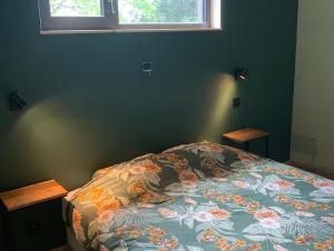 胡法利兹Le cabanon的一间卧室配有一张带花卉棉被的床和窗户。